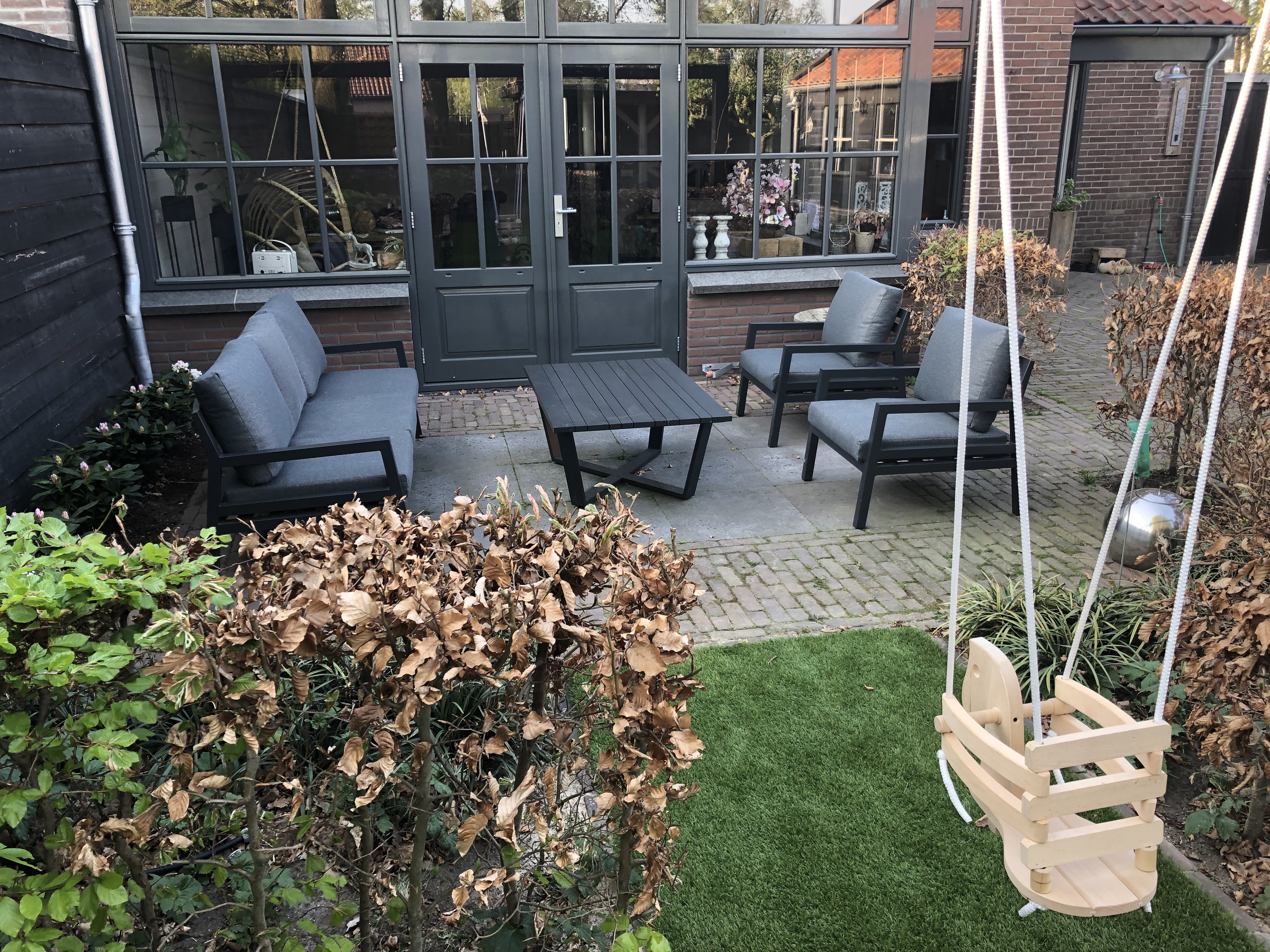Het gras is groen, de lucht is blauw, de schommel hangt, de lounge set staat!