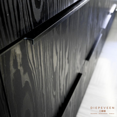 Deel van de kastjes is greep loos en een deel met greep. Deze kastjes hebben een lange dunne zwarte greep dit geeft de keuken een moderne uitstraling