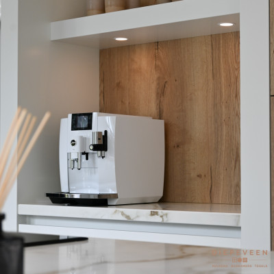 De nis is voorzien van sfeerverlichting. Om een geheel te creëren is het marmerlook werkblad ook geplaatst in de nis de achterwand is voorzien van hetzelfde eiken als de fronten.