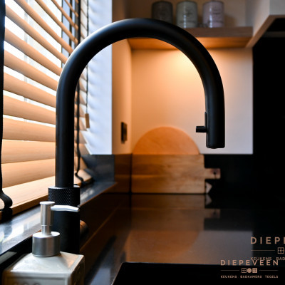 De zwarte Quooker kraan sluit zich volledig aan bij het rustig zwarte werkblad