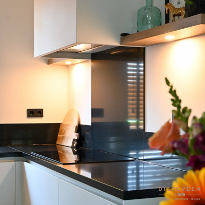 De strakke schouw geeft de keuken een stijlvolle tint waarbij op de houten planken plaats vrij is gemaakt voor wat accessoires