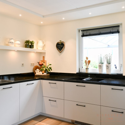 Op de witte plank is plaats voor gezellige accessoires. De spotjes geven de keuken sfeer.