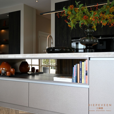 In het eiland is er plaats vrijgemaakt voor een nis. De spiegel tegen de achterkant van de nis creëert een grotere ruimte en zorgt voor een sfeervolle onderbreking in de keuken.