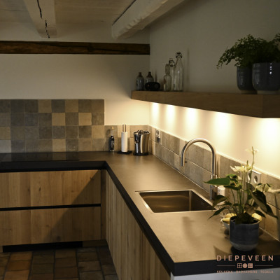 De grijslook achterwand tegels kleuren mooi bij het zwarte werkblad