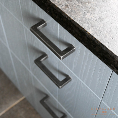 De combinatie van het zwart met motief granieten blad en de landelijke grepen met de blauwe houtlook gelakte fronten zorgen voor een landelijk karakter