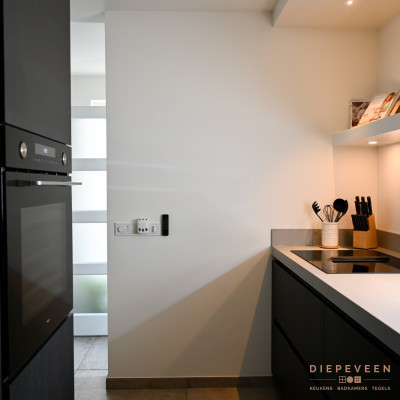 Tegenover het keukenblok is er een kast geplaatst zodat er genoeg opbergruimte vrijkomt en de magnetron op hoogte kon worden geplaatst