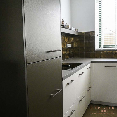 De gouden tegeltjes tegen de achterwand gecombineerd met witte fronten en bronzen fronten geeft de keuken een mooie industriële uitstraling