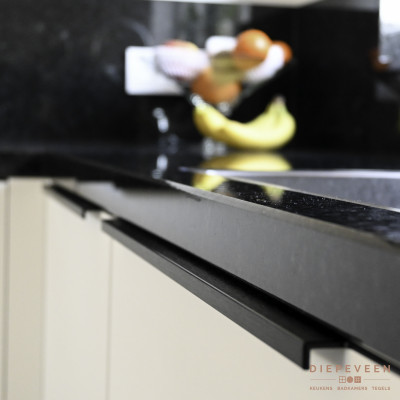 Zwart graniet werkblad in combinatie met white finemat front en een zwarte lange greep