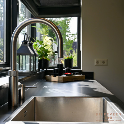 De Quooker flex met bijpassend zeeppompje is uitgevoerd in rvs wat perfect combineert met de grijze fronten.