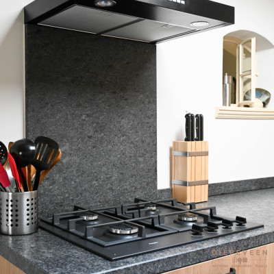 Achter de gas kookplaat is het werkblad omhoog gelegd tegen de achterwand