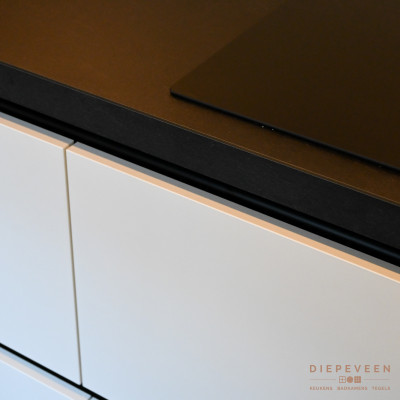 De zwarte kookplaat sluit zich volledig aan bij het werkblad en de White Finemat fronten.