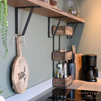 De houten plank met de groene muur geeft de keuken een landelijk tintje