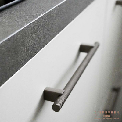 In de keuken vind je een grijs werkblad met een brons greepje en witte fronten.