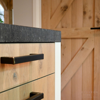 Het silestone Arden Bleu werkblad is grof afgewerkt wat perfect bij de zwart robuuste greep past. De witte ombouw maakt de keuken een fris geheel