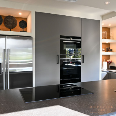 De kastenwand is voorzien van twee stijlvolle nissen met sfeerverlichting. Ook is er ruimte vrijgelaten voor het apparatuur en de Amerikaanse koelkast.