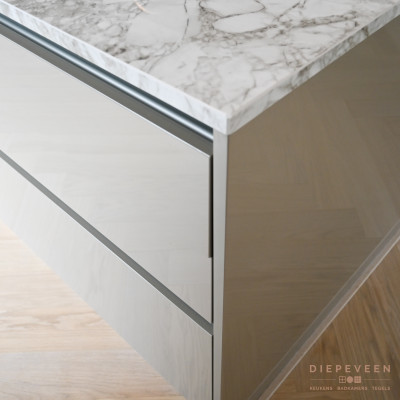 Het werkblad is van keramiek en bevat een ader die mooi combineert met het hoogglans front