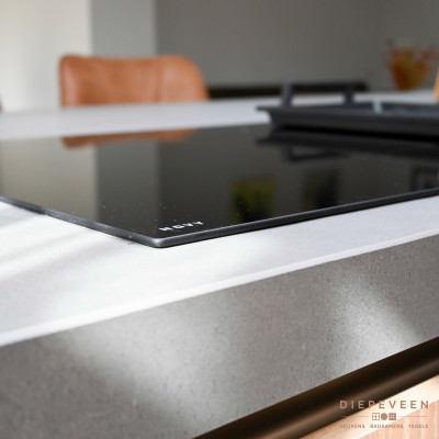 De inductiekookplaat inclusief afzuiging combineert mooi met het grijs keramiek werkblad