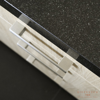 Gewerkt met een licht houtlook front, zwart werkblad in combinatie met een rvs look greep