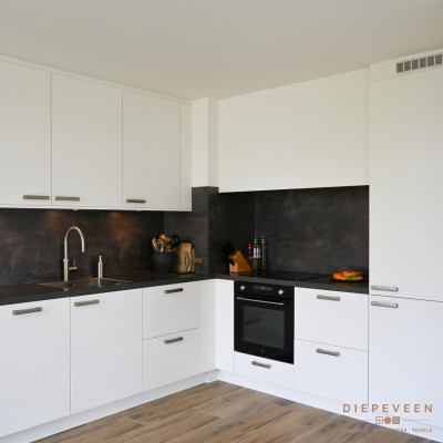 Het blad is doorgelegd tegen de achterwand wat de keuken een strakke look geeft