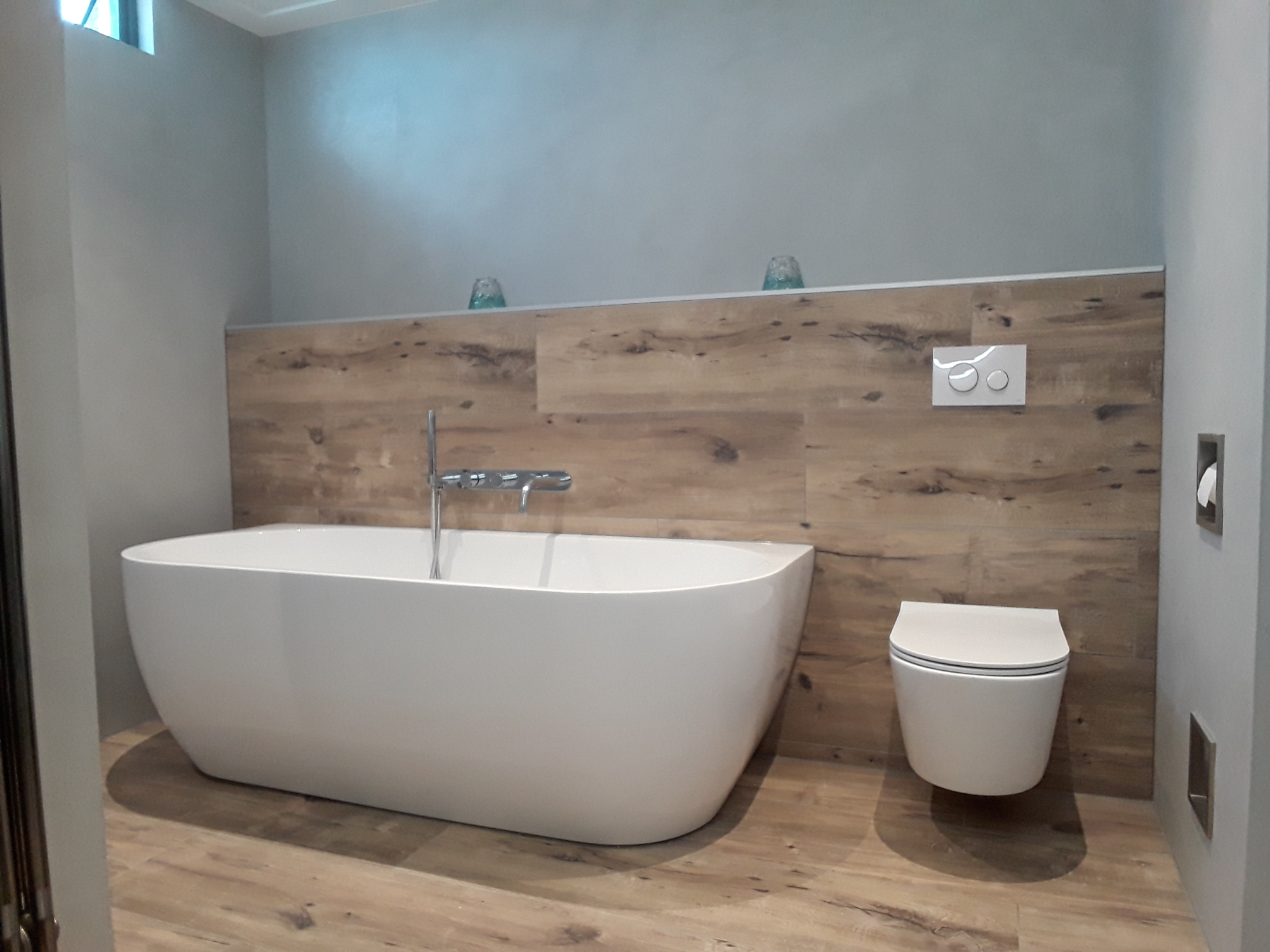 Betonlook badkamer met keramisch parket tegels en semi-vrijstaand ligbad