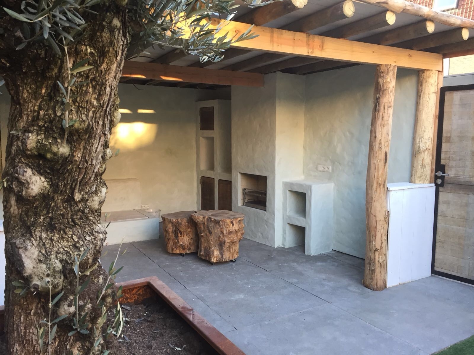 Ibiza-stijl veranda met openhaard. Op de voorgrond olijfboom.